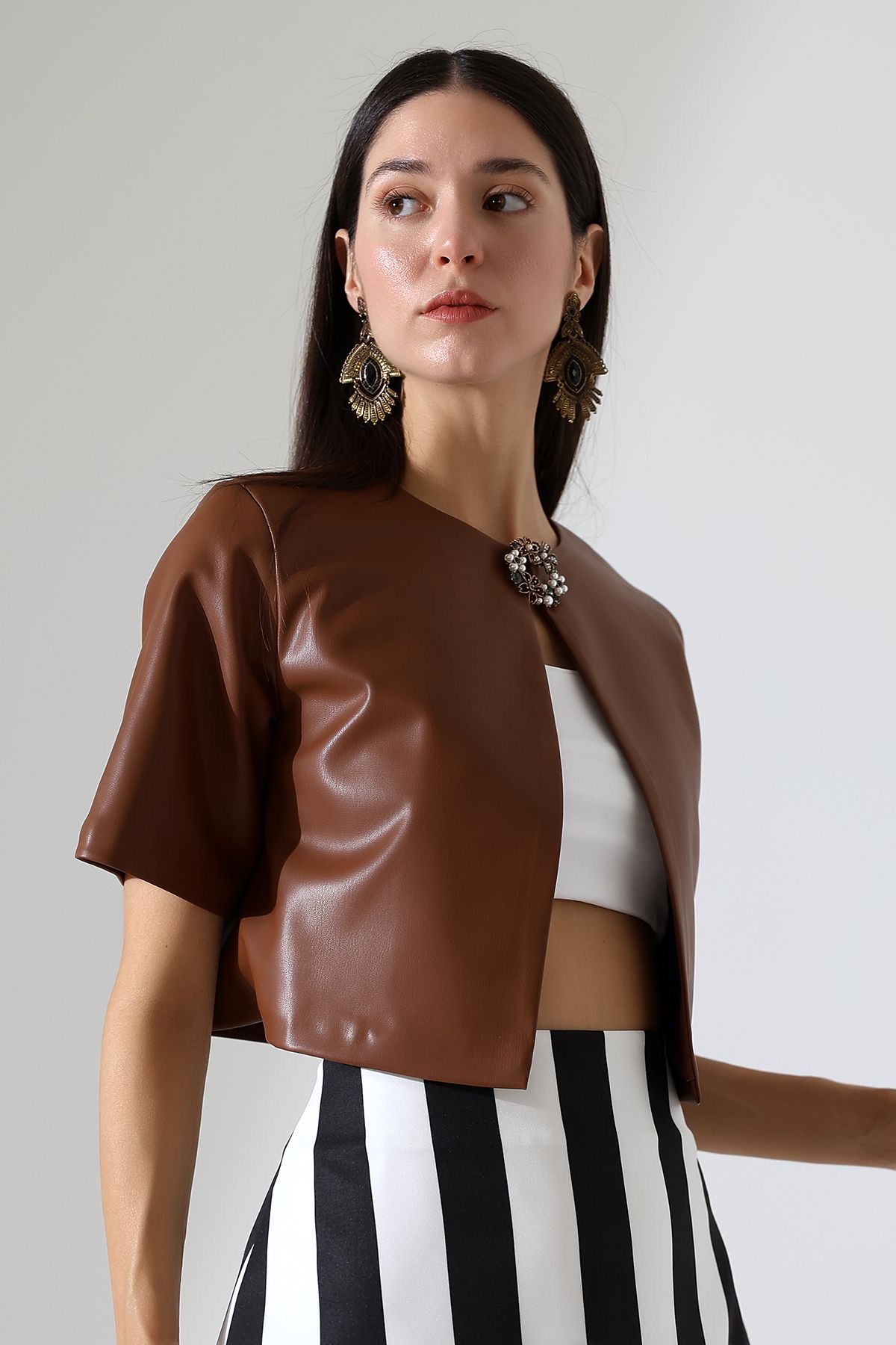 Close up of Model in striped skirt and tan leather short sleeved jacket