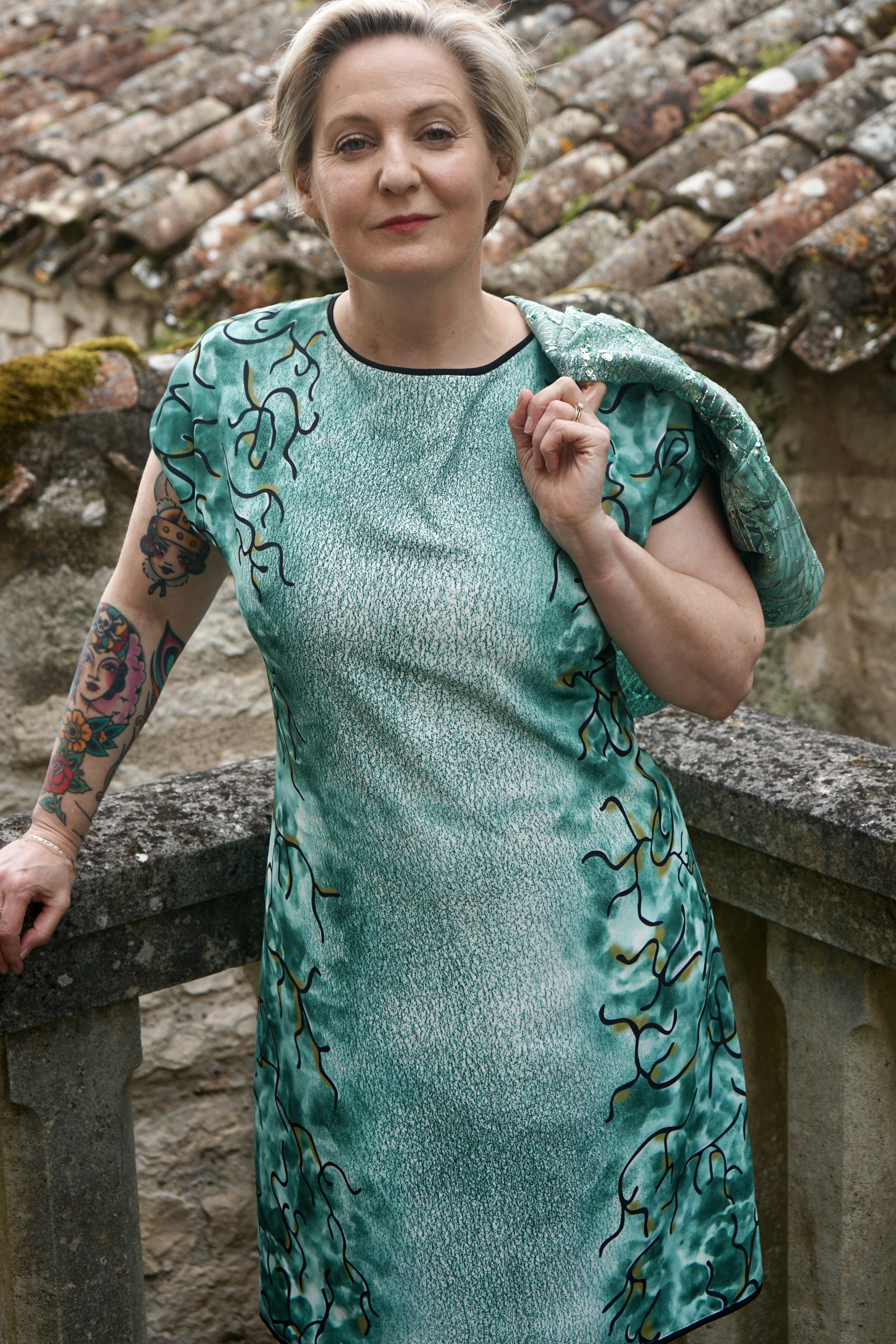 model wearing a bespoke designer green evening dress with matching bolero, featuring black interwoven designs and silver embroidery inspired by Fragonard’s Rococo art.