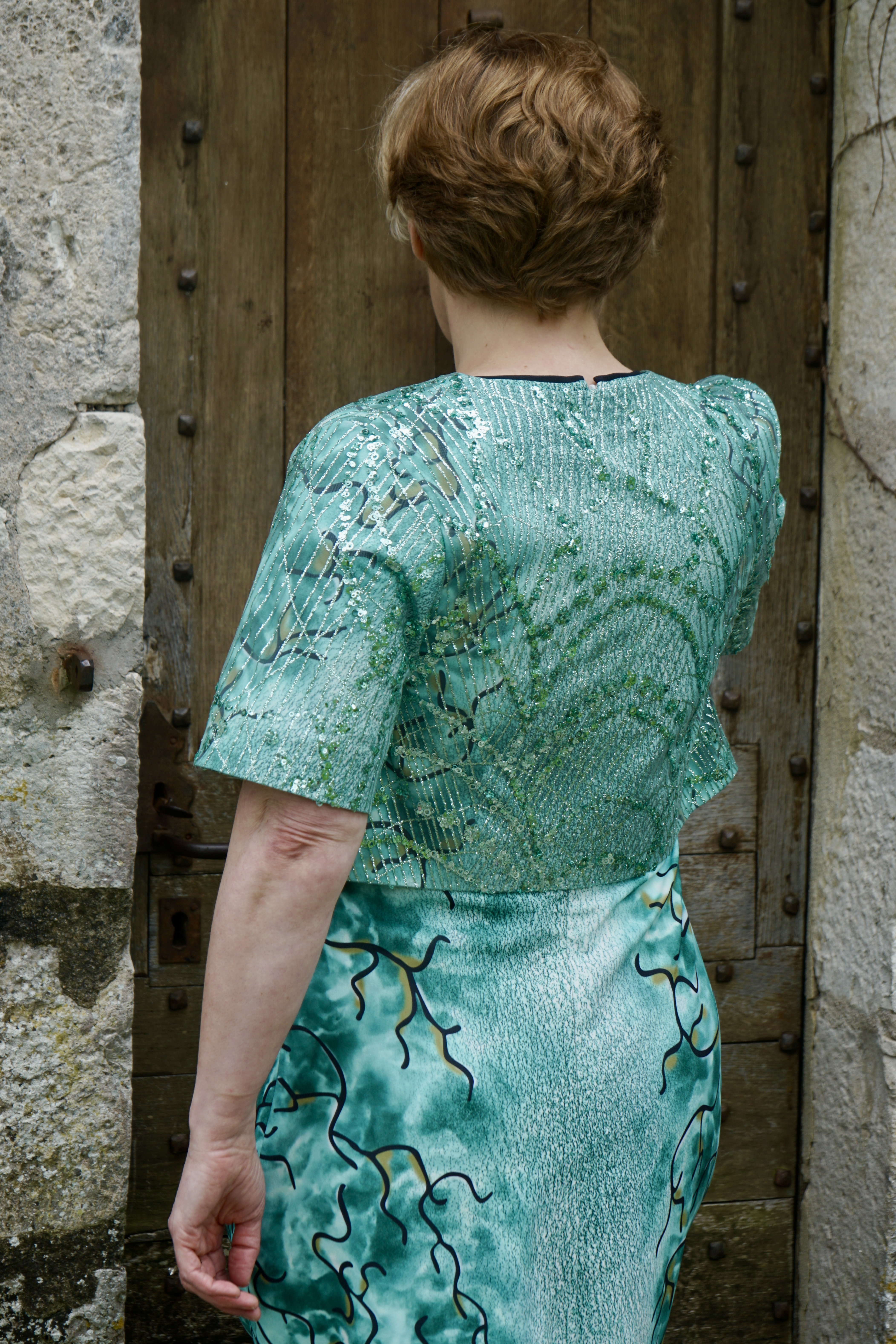 Back  of green patterned dress and pearl jacket