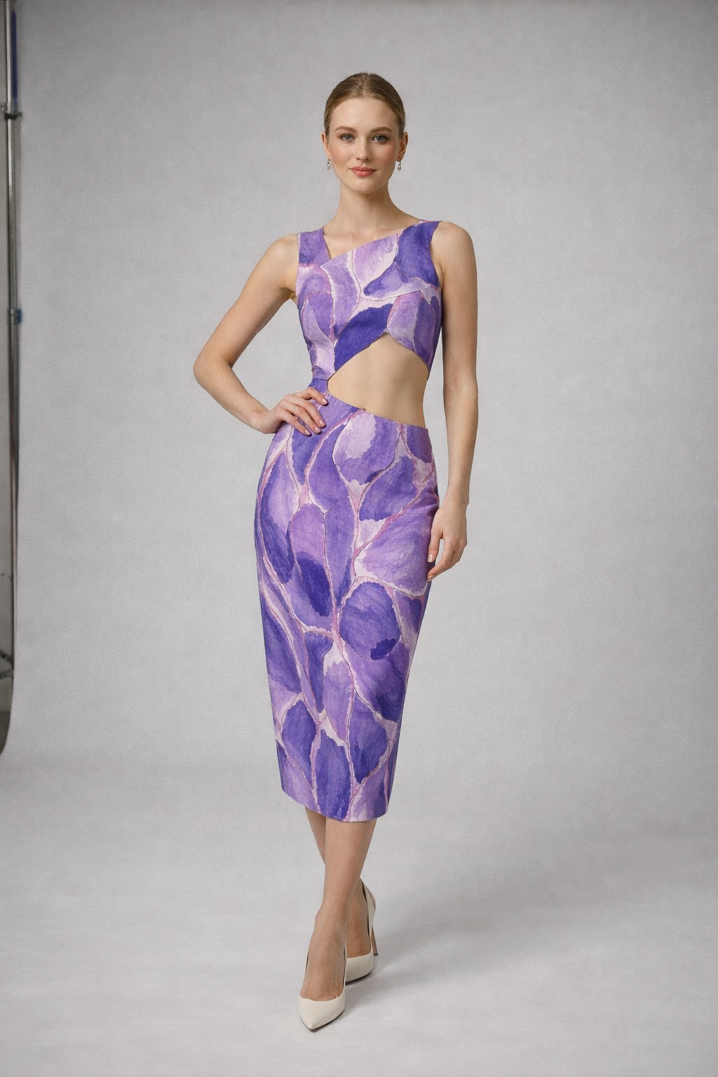 Model in mid length straight line summer dress bold purple pattern asymmetrical bodice with exposed midriff